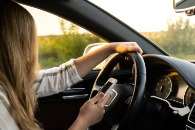 Araba kullanırken akıllı telefonuyla mesaj yollayan bir kadın. Araba kullanırken yolda cep telefonu kullanan bir kadın sürücü. Güvenlik ve teknoloji kavramı 