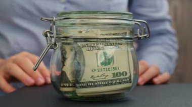 Kadın eli, Amerikan dolarlarıyla dolu cam kavanozu DREAM yazılı nakit paraya çevirir. Hazırlık para tasarrufu. Orta karar tüketim ve ekonomi. Para toplama