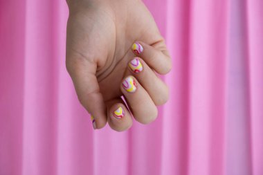 Manikürlü kadın elleri, pembe arka planda şık yaz tırnakları. Manikürlü kadın eli tırnakları. Tırnak tasarımı konseptinin yaz tarzı. Güzellik tedavisi.