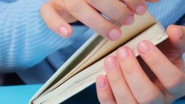 Pastel yumuşaklığı manikürlü tırnaklar ve mavi arka planda kağıt defter. Pastel paletin renginde yeni manikürünü gösteren bir kadın. Basitlik dekoru Taze bahar titreşimleri Toprak renginde nötr renkler