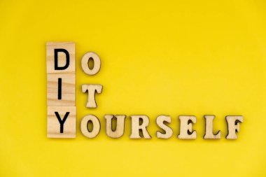 Parlak sarı arkaplandaki DIY metni. Yaratıcı el işi hobisi kavramı. Sanat terapisi aktiviteleri zihinsel sağlık iyileştirme 