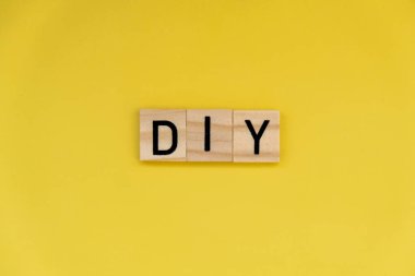 Parlak sarı arkaplandaki DIY metni. Yaratıcı el işi hobisi kavramı. Sanat terapisi aktiviteleri zihinsel sağlık iyileştirme 