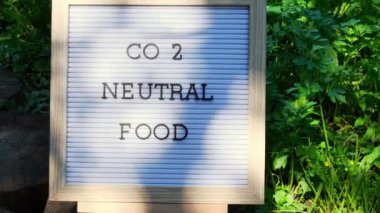 Bahçede yetişen çevre dostu yeşil maydanozun arka planında CO2 NEUTRAL Gıda Mesajı. Kırsal gıda üretim konsepti. Yerel olarak hasat üretiliyor. Sürdürülebilirlik ve sorumluluk 