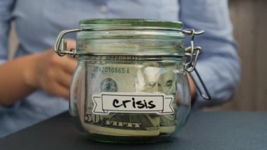 Kadın eller para dolu Glass kavanozundan para alıyor. İçinde de CRISIS yazılı nakit para. Hazırlık para tasarrufu. Orta karar tüketim ve ekonomi. Para toplama