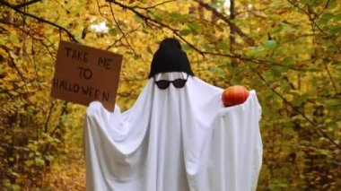 Hayalet dansı, elinde kartonla beni Cadılar Bayramı 'na ve balkabağı modasına uygun Cadılar Bayramı kutlamalarına götür. Çarşaf, kep ve gözlüklerden yapılmış el yapımı hayalet kostümü. Sonbahar ormanı portakalı