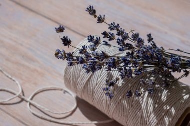 Ahşap arka planda beyaz pamuk ipin yanında lavanta çiçekleri. Aromaterapi ve organik konsept. Kurutulmuş lavanta bitkileriyle dolu bir hayat. Çevre sürdürülebilir kavram