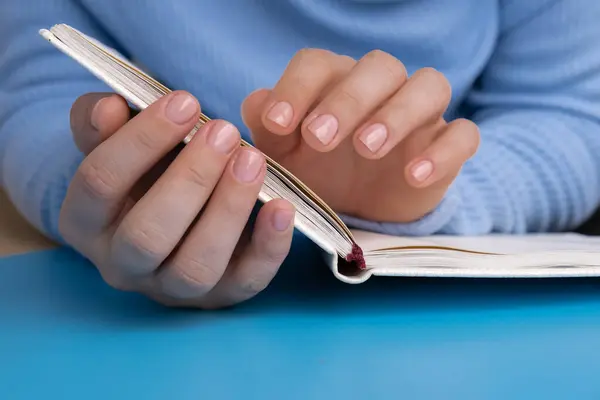 stock image Stylish nude beige female nails on paper notebook on blue background. Modern trendy stylish Beautiful manicure. Cute pastel nail minimalistic design concept of beauty treatment. Gel nails. Skin care