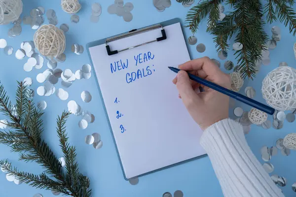 stock image Unrecognizable woman writing new years resolutions on paper note with Christmas decor. Making promises for new year, setting goals. Creating vision board motivation