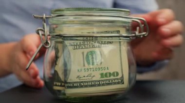 Tanınmayan bir kadın para biriktirme kavanozunu dolar banknotlarıyla doldurdu. TRAVEL transkripti kavanozun önünde. Gelecekteki güvensizlik geçmişi için kişisel finansman yöneticiliği