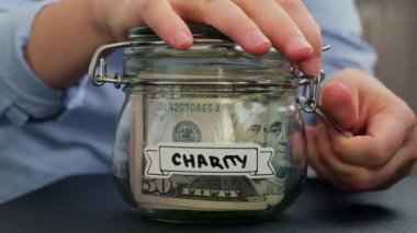 Tanınmayan bir kadın, Glass kavanozundan içi Amerikan doları dolu nakit para alıyor. Hazırlık para tasarrufu. Orta karar tüketim ve ekonomi. Para toplama
