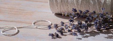 Ahşap arka planda beyaz pamuk ipin yanında lavanta çiçekleri. Aromaterapi ve organik konsept. Kurutulmuş lavanta bitkileriyle dolu bir hayat. Çevre sürdürülebilir kavram