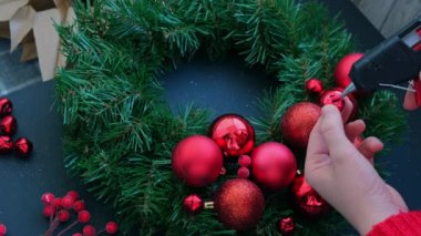 Adım adım el yapımı Noel çelengi yapma talimatı. Kırmızı renkli şenlik süslerinden yapılmış. Kadın elleri el yapımı dekorasyon yapıyor. Yeni yıl kutlaması. Kış tatili Adım 1