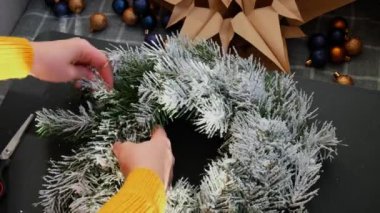 Adım adım, mavi ve sarı renklerle süslenmiş el yapımı Noel çelengi yapma talimatı. Kadın elleri el yapımı dekorasyon yapıyor. Yeni yıl kutlaması. Kış tatili