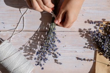 Kuru lavanta çiçeği buketleri yapan bir kadın. Ev yapımı otlardan kokulu buketler ve kese yapma süreci. Adım adım alternatif tıp. ÇEVİR