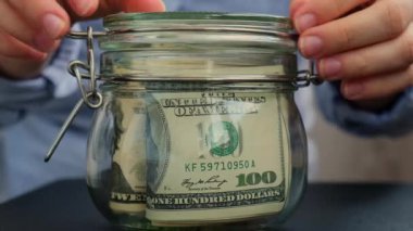 Para biriktiren kadın elleri dolar banknotlarıyla dolu cam kavanozu dönüştürür. Kopyasını kavanozun önüne koy. Gelecekteki güvensizlik geçmişi için kişisel finansman yöneticiliği