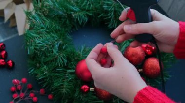 El sanatları ustası, bir kadının kırmızı dekorlu Noel düzenlemesi için sıcak yapıştırıcı kullanıyor. Küçük işletme, serbest meslek sahibi girişimci, kendi kendini yetiştirmiş bir kariyer. El yapımı zanaat talimatları serisi