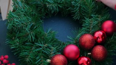 El sanatları ustası, bir kadının kırmızı dekorlu Noel düzenlemesi için sıcak yapıştırıcı kullanıyor. Küçük işletme, serbest meslek sahibi girişimci, kendi kendini yetiştirmiş bir kariyer. El yapımı zanaat talimatları serisi