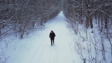 Kış ormanlarında Noel Baba şapkası takan bir adam. Hava manzaralı güzel karlı ağaçlar. Kış mevsiminde yol. Soğuk sabah seyahati konsepti. İnanılmaz kış sahnesi. Noel teması. Ladin kaplı