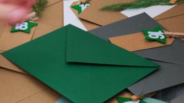 El işi zarflarındaki numaralar, Noel tatilinden önce notları görevlerle doldurur. El yapımı takvim için el yapımı Kraft kağıdı yapan bir kadın. Kendi ellerinle adım adım kendin yap. 