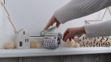 Cam kavanoz ve tatlı çikolata şekerlerinden yapılmış Orijinal Advent Takvimi 'nden şeker alan kadın Noel konsepti. Kış tatiline kadar geri sayım. El yapımı takvim. Adım adım DIY el sanatları yapar