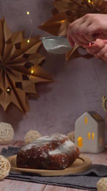 Geleneksel Alman Noel pastası, arka planda el yapımı şenlik dekorunun üzerine düşen şeker tozu ile birlikte. Dikey Kış tatili hediyeleri. Vejetaryen yemek tarifi hazırlama