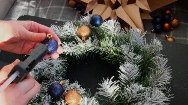 Şenlikli mavi ve sarı süslemelerden elde yapılmış el yapımı Noel çelengi kullanan el sanatları ustası. Tatil hazırlığı, yaratıcı dekorasyon ustası sınıfı. Etkin faaliyetler sürdürülebilir