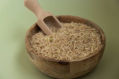 Yeşil arka planda esmer pirinç kopyalama alanı. Tam hecelenmiş tahıl türü. Yüksek proteinli lif zengini vejetaryen gıda bileşeni. Glütensiz süper yiyecekler sağlıklı beslenme alternatifleri 