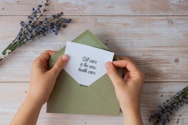 SELF CARE, yeşil zarftan gelen destekleyici mesaj kâğıdı anımsatıcısının yeni Sağlık Bakım Metni 'dir. Düz kompozisyon, kuru lavanta çiçekleri. İçsel mutluluk kavramı, kişisel tatmini yavaşlatan dijital detoks. Üst görünüm