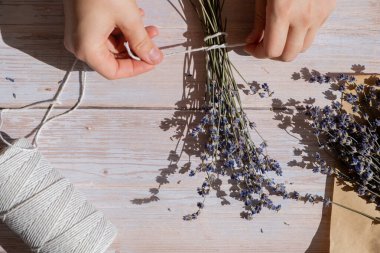 Kuru lavanta çiçeği buketleri yapan bir kadın. Ev yapımı otlardan kokulu buketler ve kese yapma süreci. Adım adım alternatif tıp. ÇEVİR