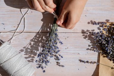 Kuru lavanta çiçeği buketleri yapan bir kadın. Ev yapımı otlardan kokulu buketler ve kese yapma süreci. Adım adım alternatif tıp. ÇEVİR