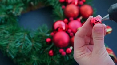 Şenlikli kırmızı süslemelerden elde yapılmış el yapımı Noel çelengi kullanan el sanatları ustası. Tatil hazırlığı, yaratıcı dekorasyon ustası sınıfı. Etkin faaliyetler sürdürülebilir sorumluluk