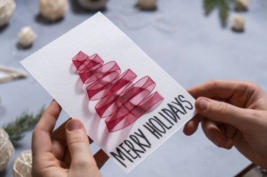 Noel ağacı kurdelesi hediye Noel fikri. Kendin yap. Kartpostalla çevre dostu dekorasyon yap. El yapımı hediyeler yapmak çocuklar için zararsız projeler. Tatil aile zamanı. Yaratıcı etkinlik