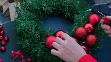 Adım adım el yapımı Noel çelengi yapma talimatı. Kırmızı renkli şenlik süslerinden yapılmış. Kadın elleri el yapımı dekorasyon yapıyor. Yeni yıl kutlaması. Kış tatili Adım 1