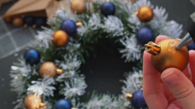 Şenlikli mavi ve sarı süslemelerden elde yapılmış el yapımı Noel çelengi kullanan el sanatları ustası. Tatil hazırlığı, yaratıcı dekorasyon ustası sınıfı. Etkin faaliyetler sürdürülebilir