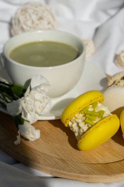 Dağınık yatağın üzerinde sarı ve beyaz badem kurabiyeli yeşil latte. Tatil kahvaltısı çay içeceği kavramı. Sıcacık minimalist süper yiyecekler canlı renkler sağlıklı beslenme. Organik kafeinsiz.