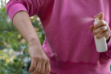 Yazın açık havada eline böcek ilacı sıkan biri var. Sivrisinekleri ve sinekleri öldürmeye çalışıyor. Bariz bir şekilde damlacıklar. Güneşli bir günde sivrisinek ısırığına karşı korunma.