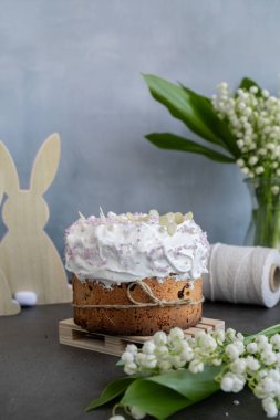 Ev yapımı Paskalya pastası kremalı ve yaratıcı dekorasyon yiyecekli panettone. Hıristiyan bayramı için hazırlık Kulich. Arka planda Paskalya yumurtası ve tavşan var. 