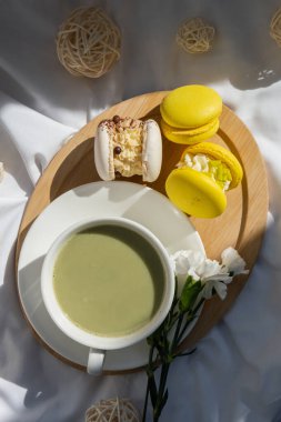 Besin zengini kibritçi içeceği. Yatakta ahşap tepside taze çiçeklerle modadan yapılmış makarna tatlısı. Günaydın güzel kahvaltı hediyesi fikri. Canlı yaratıcı renkler. Doğal enerji çay verir.