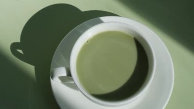 Pastel arka planda yeşil latte matcha ve yaratıcı derin gölgeler. Tatil kahvaltısı çay içeceği kavramı. Sıcacık minimalist süper yiyecekler canlı renkler sağlıklı beslenme. Organik kafeinsiz.