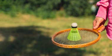 Neon sarısı badminton topu ve ahşap raket tutan bir kadın. Mekik horozlarına yumuşak seçici odak kopyala. Alternatif fitness eğlence sporu