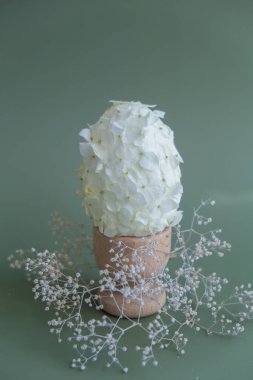 Beyaz leylak bahar çiçeklerinden yapılmış yaratıcı Paskalya yumurtası. Sorumlu tatil dekorasyonu. Minimum tatil konsepti hala hayat. Boşluk tebrik kartı kopyala 