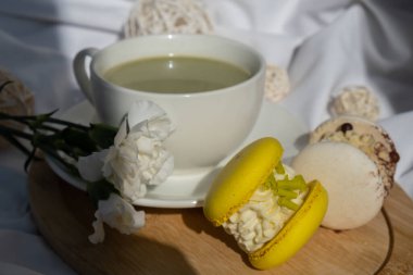 Dağınık yatağın üzerinde sarı ve beyaz badem kurabiyeli yeşil latte. Tatil kahvaltısı çay içeceği kavramı. Sıcacık minimalist süper yiyecekler canlı renkler sağlıklı beslenme. Organik kafeinsiz.