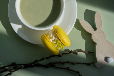 Sarı badem kurabiyeli yeşil latte kibriti ve EASTER sürdürülebilir dekorasyonu. Tatil kahvaltısı çay içeceği kavramı. Sıcacık minimalist süper yiyecekler canlı renkler sağlıklı beslenme. Organik
