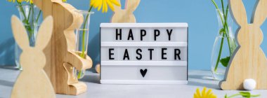 Lightbox with message HAPPY EASTER on festive blue background and eco-friendly zero waste natural decoration. Yellow daisies flowers. Holiday greeting card clipart