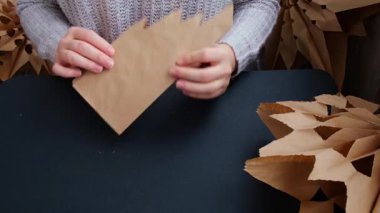 El işi kağıt torbaları Noel yıldızı ve yeni yıl arifesi için hazırlanan kar tanelerine dönüşür. Üç boyutlu el çantası kar tanelerini boyamış. Sorumlu ekolojik sıfır atık el yapımı dekorasyon. Çocuklar
