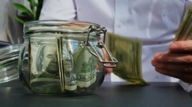 Dolar banknotu cam kavanozda para biriktiriyor. Tanınmayan Adam Orta Yol Tüketim ve Ekonomi Para Bahşişi Topluyor İş Finans Görüntüleri