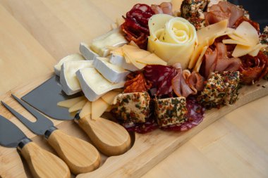 Peynir ve et şarküteri tahtası. Hediye hediyesi, öğle yemeği tabağı. Görsel olarak en az çaba gerektiren atıştırmalıklar. Özel peynir bıçaklarıyla basit bir yemek hazırlama. Tahta.