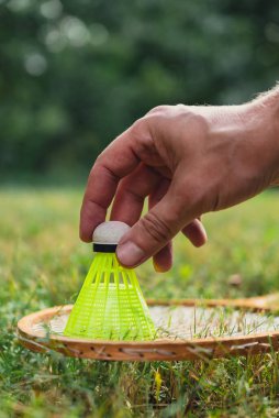 Neon sarısı badminton mekik horozu ve açık havada yeşil çimlerde raket. Mekik horozlarına yumuşak seçici odak kopyala. Alternatif fitness eğlence sporu