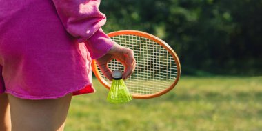 Neon sarısı badminton topu ve ahşap raket tutan bir kadın. Mekik horozlarına yumuşak seçici odak kopyala. Alternatif fitness eğlence sporu