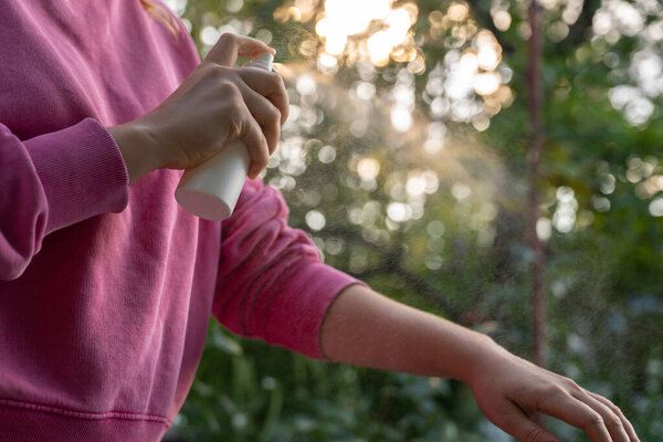 Человек, распыляющий средство от насекомых на улице летом. Пытается убить комаров и мух. Четко видны капли спрея. Профилактика дезинфекции против укусов комаров в солнечный день